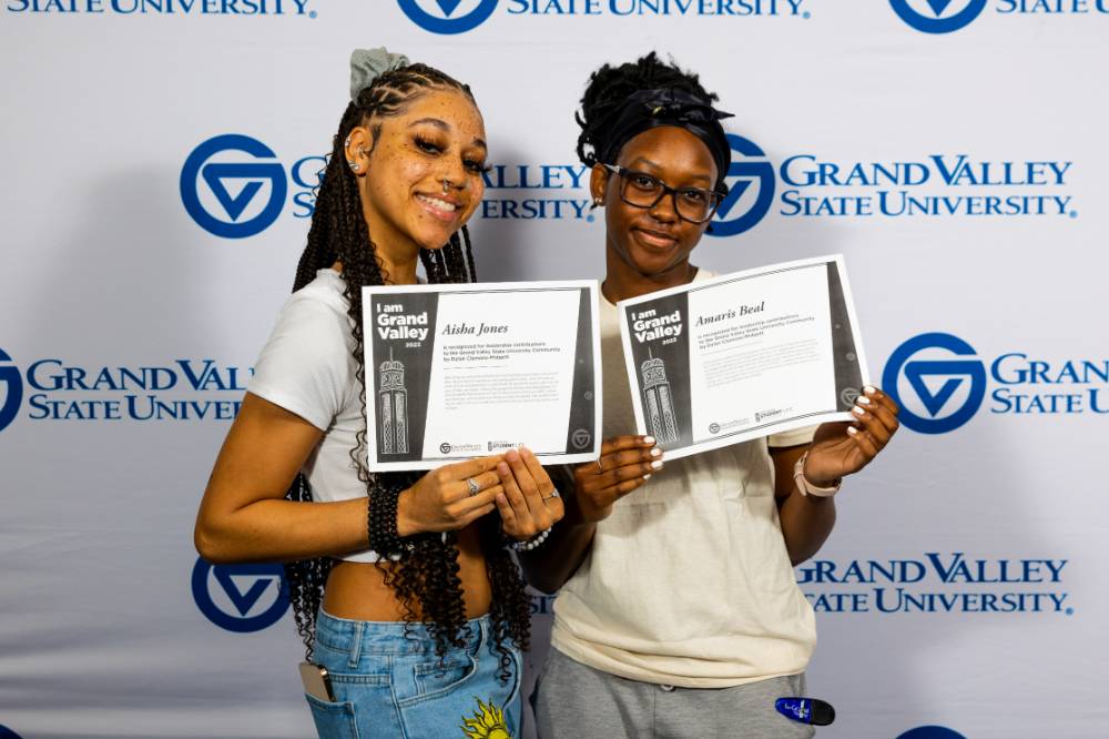 individuals smiling holding two certificates together